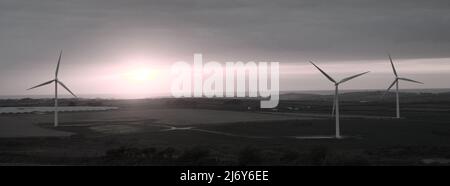 Un panorama couleur réduit de trois éoliennes et d'une ferme solaire contre un coucher de soleil dans un paysage de Cornouailles du Nord. Parc éolien de Carland Cross, Cornwall, Royaume-Uni Banque D'Images