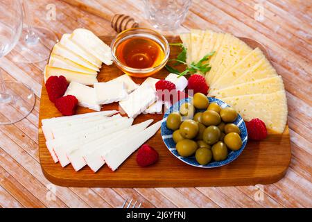 Différents types de fromage, miel, framboises et olives sur bois Banque D'Images