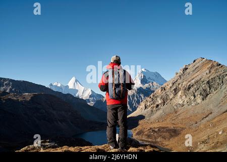 vue arrière de l'homme asiatique randonneur mâle regardant les montagnes dans le parc national de yading, comté de daocheng, province du sichuan, chine Banque D'Images