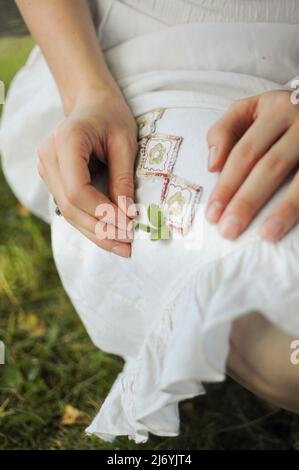 Gros plan ethnique d'une robe blanche. Une femme tient en main une petite plante. Concept d'été Banque D'Images