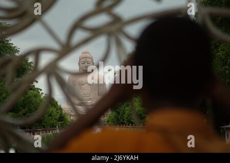 Un moine faisant attention à une statue de 64 pieds de haut du Grand Bouddha derrière la clôture à Bodh Gaya, Bihar, Inde. Il a été construit dans une pose de méditation à partir d'un mélange de grès et de granit rouge par l'artiste V. Ganapati Sthapati de 1982 à 1989. Banque D'Images