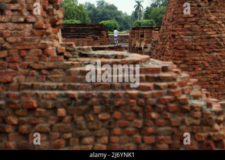 Un visiteur est photographié à travers des ruines de structures en briques au complexe Dhamek stupa à Sarnath, à la périphérie de Varanasi, Uttar Pradesh, Inde. Banque D'Images