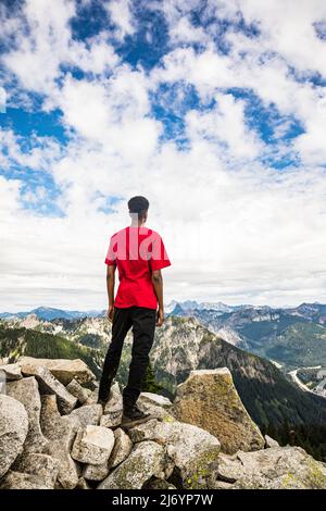 Un jeune homme se tenant au sommet de Granite Peak dans les Cascades de Washington en regardant la vue. Banque D'Images