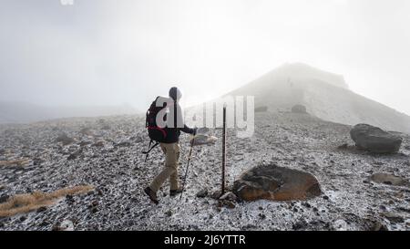 Randonnée sur le terrain escarpé de la carie jusqu'au sommet du cratère Rouge dans le brouillard épais de Tongariro Alpine Crossing. Nouvelle-Zélande. Banque D'Images