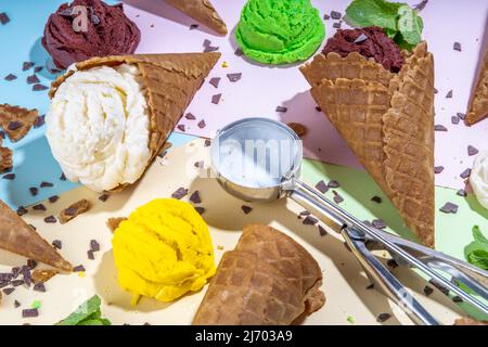 Collection de crème glacée brillante dans des cornets de gaufres, ensemble de crème glacée de différentes saveurs sur fond coloré plat espace de copie Banque D'Images