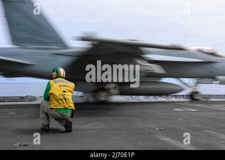 MER DES PHILIPPINES (19 avril 2022) le chef de l’aviation Boatswain’s Mate (Equipment) Dustin Nichols, de Commerce (Géorgie), signale un F/A-18E Super Hornet, affecté aux « vigilantes » du Strike Fighter Squadron (VFA) 151, sur le pont de vol du porte-avions de la classe Nimitz USS Abraham Lincoln (CVN 72). Abraham Lincoln Strike Group est en cours de déploiement prévu dans la zone d'exploitation de la flotte américaine 7th afin d'améliorer l'interopérabilité par le biais d'alliances et de partenariats tout en servant de force d'intervention prête à l'emploi pour soutenir une région Indo-Pacifique libre et ouverte. (É.-U. Photo de la marine par un spécialiste des communications de masse Banque D'Images