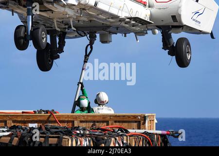 MER DES PHILIPPINES (28 avril 2022) Spécialiste en logistique le marin Cameron Mudgett, à gauche, de Carlsbad, en Californie, et le spécialiste en logistique en chef Willie Bates, d'Elizabethtown, en Ky., placez un crochet de chargement sur un Super Puma AS332 sur le pont de vol du porte-avions de la classe Nimitz USS Abraham Lincoln (CVN 72) Au cours d'une reconstitution verticale en mer avec le navire de fret et de munitions du Commandement militaire maritime USNS Cesar Chavez (T-AKE 14). Abraham Lincoln Strike Group est en cours de déploiement prévu dans la zone d'exploitation de la flotte américaine 7th afin d'améliorer l'interopérabilité par le biais d'alliances et de partenariats W Banque D'Images