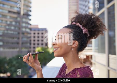 Une jeune femme envoie une note vocale sur le balcon d'un immeuble de bureaux de la ville Banque D'Images