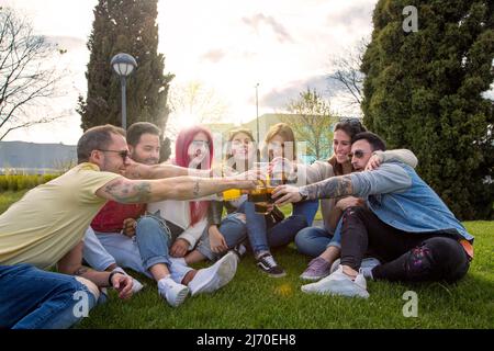 groupe d'amis assis dans le jardin buvant un toast Banque D'Images