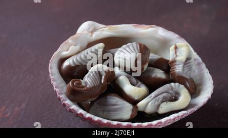 Bonbons au chocolat traditionnels aux coquillages belges. Bonbons au chocolat au lait belge en forme de coquillages avec palourdes, hippocampes Banque D'Images