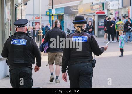 Un agent de police et un agent de soutien communautaire de la police qui traversent le centre-ville de Newquay à Cornwall, au Royaume-Uni. Banque D'Images