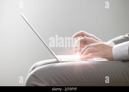 Homme d'affaires tapant sur un ordinateur portable hautes performances ultra-fin et léger sur les genoux avec confort de travail et mobilité. Banque D'Images