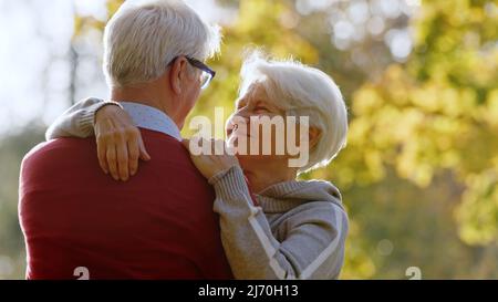 Charmant couple hétérosexuel de race blanche. Portrait extérieur de deux retraités âgés qui s'embrasent dans le parc, profitant d'un beau temps ensoleillé. Concept de relations longues. Photo de haute qualité Banque D'Images