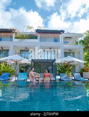 Praslin Seychelles, couple hommes et femmes dans la piscine pendant les vacances dans un complexe de luxe à la plage de l'île tropicale d'Anse Volbert avec des plages de sable et des palmiers Banque D'Images