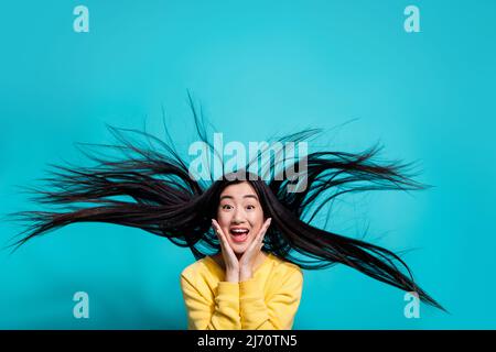 Photo de charmante dame impressionnée vêtue jaune chandail bras joues vent soufflant isolé couleur turquoise fond Banque D'Images