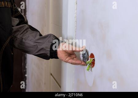 Un électricien installe le commutateur d'éclairage dans le mur Banque D'Images