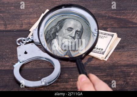 Menottes sur une semaine de dollars à travers une loupe, Benjamin Franklin gros plan. Banque D'Images