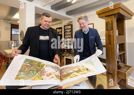 05 mai 2022, Thuringe, Eisenach: Jochen Birkenmeier (r), directeur scientifique et conservateur de la Fondation Luther House Eisenach, et Martin Wiedmann, fils de l'artiste, regardent le livre après avoir remis une Bible Wiedmann à la Maison Luther Eisenach. La Bible de l'artiste de Stuttgart W. Wiedmann (1929-2013) se compose de 3333 images et est la seule Bible au monde qui reproduit l'ancien et le Nouveau Testament en images. Photo: Michael Reichel/dpa Banque D'Images