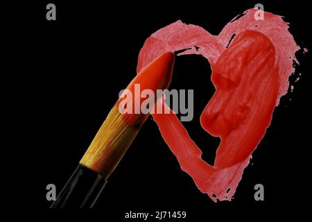 Pointe de la brosse de l'artiste trempée en acrylique rouge sur coeur peint partiellement terminé sur fond noir Banque D'Images