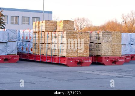grandes piles de planches en bois sur les remorques de fret dans le port. Banque D'Images