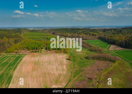 Une vaste plaine couverte de terres arables et de prairies. Vous pouvez voir des touffes d'arbres à certains endroits. Le ciel est légèrement nuageux. Photo du drone. Banque D'Images