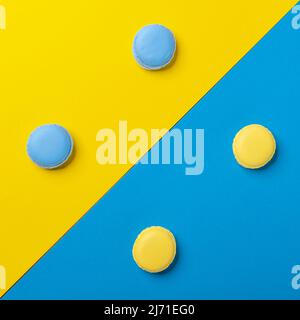 Les macarons bleu et jaune sont disposés symétriquement sur un arrière-plan de couleur opposée Banque D'Images