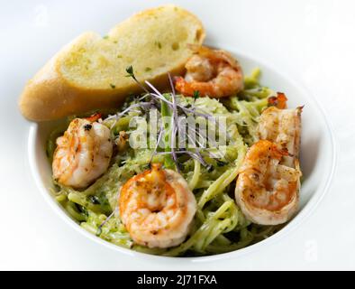 Pesto spaghetti recouvert de crevettes et de pain à l'ail Banque D'Images