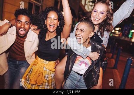 Groupe d'amis qui rient et vivent leur meilleure vie dans la ville. Les jeunes heureux s'amusent tout en se traînant ensemble la nuit. Des amis dynamiques Banque D'Images
