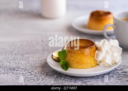Crème caramel dessert ou flan décoré de crème fouettée et de menthe et servi avec une tasse de café. Arrière-plan pour un moment agréable. Banque D'Images