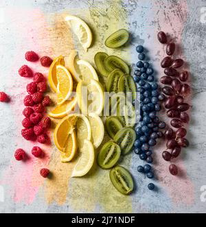 Fruits coupés et disposés dans l'ordre des couleurs arc-en-ciel. Quelques coups de pinceau de couleurs arc-en-ciel. Gay Pride Day, concept LGBT. Banque D'Images