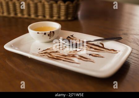 Gros plan de la cuillère sale après avoir mangé un gâteau au chocolat sur une assiette blanche dans le café Banque D'Images