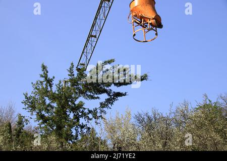 La flèche d'une grue de construction s'accroche au sommet d'un arbre Banque D'Images