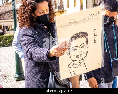 Une femme en masque de visage regardant le portrait dessiné dans le marché de Grenade nous aimons. Grenade, Espagne Banque D'Images