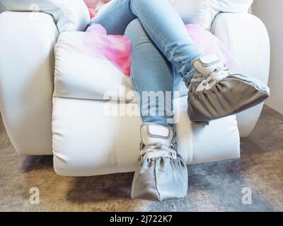 Femme dans des couvre-chaussures assis dans un fauteuil d'hôpital de près Banque D'Images