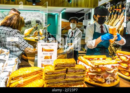 Café Pastelería López-Mezquita. Sandwiches, fast food, gâteaux exposés derrière la fenêtre avec masque facial. Février 2022. Grenade, Espagne Banque D'Images