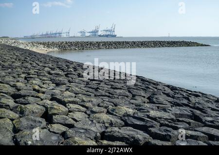 Le bord de mer est fortifié avec des pierres provenant du lavage par l'eau, un port peut être vu en arrière-plan. Magnifique paysage de mer. Banque D'Images