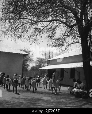 Les filles soudanaises train pour être enseignants. Ils apprennent dans les salles de classe de Grass Hut jusqu'à ce que le New College soit prêt. Assis sous un arbre trois des stagiaires de l'enseignant de fille notent les différents mouvements de la P.T. forer dans une école primaire voisine. Il y a aussi un grand centre d'éducation pour les garçons à Dilling, qui est le centre administratif du district de Nuba Mountain. Aucun Nubas n'a jusqu'à présent participé au centre de formation des filles, mais pourrait être inscrit plus tard. 14 mai 1953. (Photo du Bureau central d'information). Banque D'Images