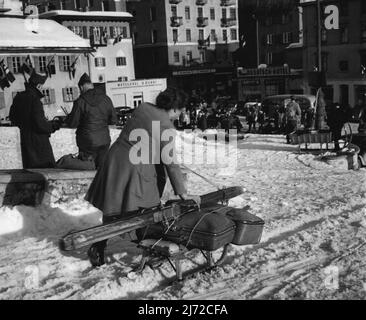 Saint-Moritz (5) de l'ensemble de six -- c'est la méthode la plus facile pour se rendre d'un endroit à l'autre sur une femme suisse avec des sacs et des skis sur un traîneau pousse le long de la rue enneigée. 20 février 1948. (Photo d'ACME). Banque D'Images