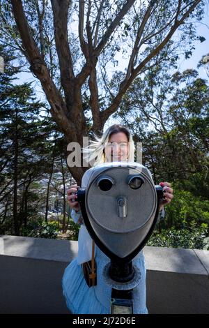 Jeune femme utilisant des jumelles touristiques à Coit Tower à San Francisco | Tourisme de style de vie Banque D'Images