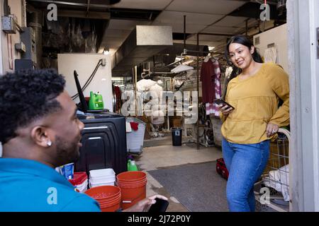 Homme et femme travaillant dans une petite entreprise de nettoyage à sec Banque D'Images