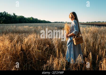 Connectez-vous à la nature, ralentissez, soyez présent, entrez dans vos sens. Paisible seule jeune femme en robe marchant sur le champ de blé au coucher du soleil le jour d'été Banque D'Images
