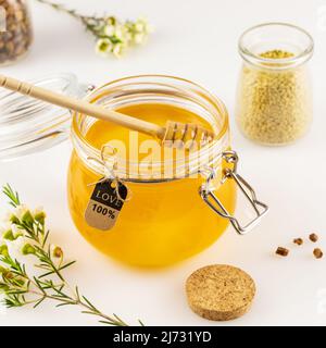 Composition de soins de santé avec miel organique et propolis en pots de verre avec un balancier de miel sur une table blanche avec fleurs. Les produits de l'abeille sont un naturel, fol Banque D'Images