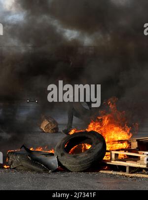 (220505) -- NAPLOUSE, le 5 mai 2022 (Xinhua) -- Un manifestant palestinien brûle des pneus lors d'affrontements avec des soldats israéliens à la suite d'une manifestation en faveur des Palestiniens à Jérusalem, au point de contrôle de Hawara, dans la ville de Naplouse, en Cisjordanie, le 5 mai 2022. (Photo d'Ayman Nobani/Xinhua) Banque D'Images