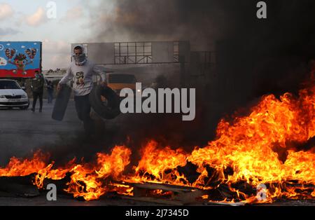 (220505) -- NAPLOUSE, le 5 mai 2022 (Xinhua) -- Un manifestant palestinien brûle des pneus lors d'affrontements avec des soldats israéliens à la suite d'une manifestation en faveur des Palestiniens à Jérusalem, au point de contrôle de Hawara, dans la ville de Naplouse, en Cisjordanie, le 5 mai 2022. (Photo d'Ayman Nobani/Xinhua) Banque D'Images
