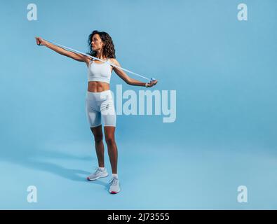 Femme forte utilisant une bande de résistance. Femme de fitness faisant un entraînement d'étirement en studio. Banque D'Images
