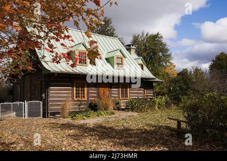 Ancienne maison en rondins de style Canadiana 1800s avec cour avant paysagée en automne. Banque D'Images