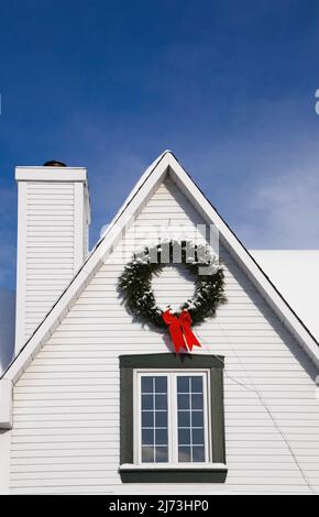 Vue partielle sur une maison de style Canadiana à deux étages décorée de couronnes de Noël en hiver. Banque D'Images
