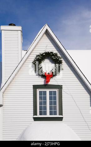 Vue partielle sur une maison de style Canadiana à deux étages décorée de couronnes de Noël en hiver. Banque D'Images