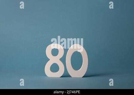 Bois blanc numéro quatre-vingt 80 sur fond bleu. Banque D'Images