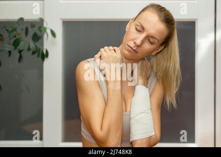 Belle jeune femme pratiquant le sport à la maison. La forme physique sportive s'étire sur les points de douleur. Massage du dos. Concept de sport et de modes de vie sains. Photo de haute qualité Banque D'Images